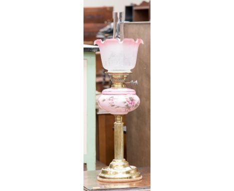 A late Victorian brass oil lamp with pink glass reservoir/shade