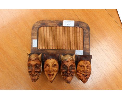 A 'Devils Head' pipe rack, Edwardian, carved box wood and painted with oak back