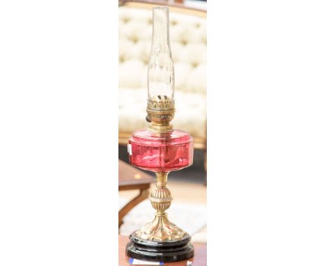 A late Victorian brass oil lamp with ruby glass reservoir (no shade)