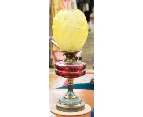 A cranberry glass oil lamp on metal base, with yellow glass shade, and chimney