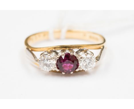 An 18 ct gold ruby and diamond three stone ring, central ruby approx. 5 mm round, two round cut brilliant diamonds approx. we