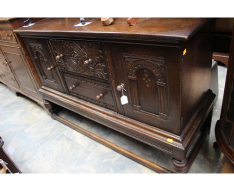 A Jacobean style oak sideboard, fitted with two doors and two drawers, raised on a base section with cup and cover legs 90 cm