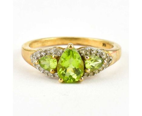 A 9ct gold dress ring with claw set pear-shaped peridot flanked by two claw set peridots within borders of white tiny stones,