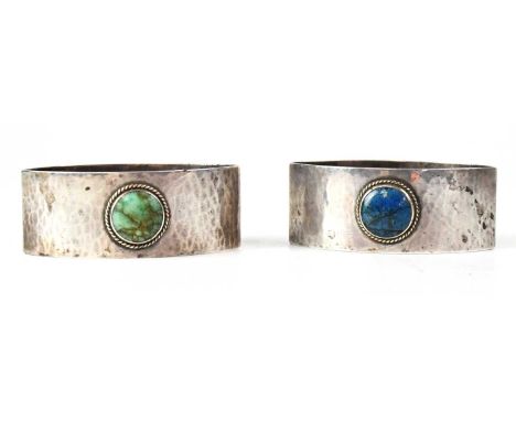 LIBERTY &amp; CO; a pair of George V hallmarked silver hammered napkin rings, each set with a cabochon stone, Birmingham 1926