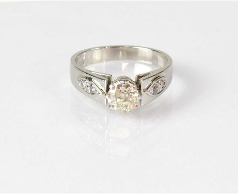 A platinum solitaire diamond ring, the diamond in a claw setting, with smaller diamond chips set to each shoulder, stamped 'P