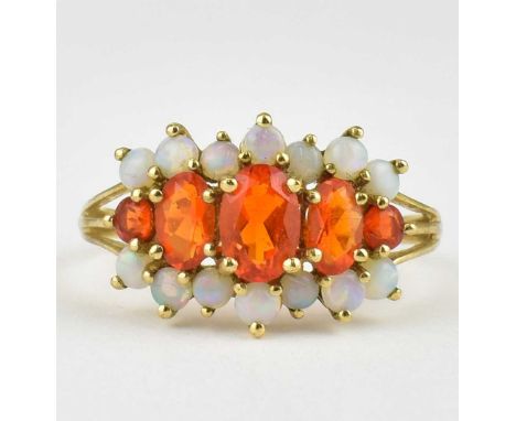 A 9ct gold ring set with five graduated marquise cut firestone opals, flanked by various round claw set white opals, size P, 