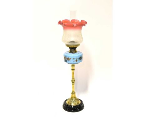 A Victorian brass oil lamp with painted blue glass well and a matched etched cranberry and opaque glass shade, height 74cm.