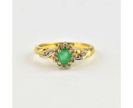 An 18ct gold ring with marquise cut claw set emerald within a border of small white stones, white stone to each shoulder, siz