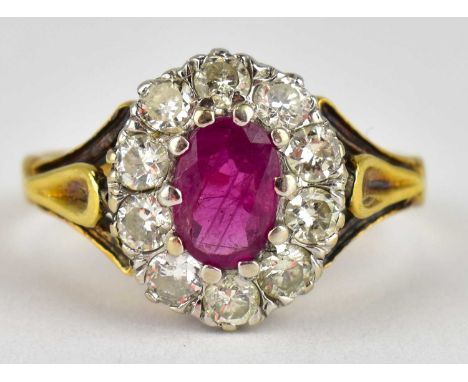 A 9ct gold ring with claw set oval cut ruby within a border of claw set tiny brilliant diamonds, split shoulders, size L, app
