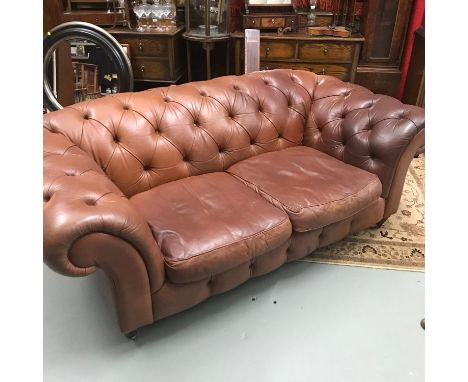 A Chesterfield button back tan leather two seater settee. On brass castor feet. 