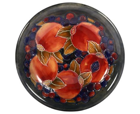 A Moorcroft Pomegranate design dish, with dark blue and green ground background, signed and stamped to base with maker's labe