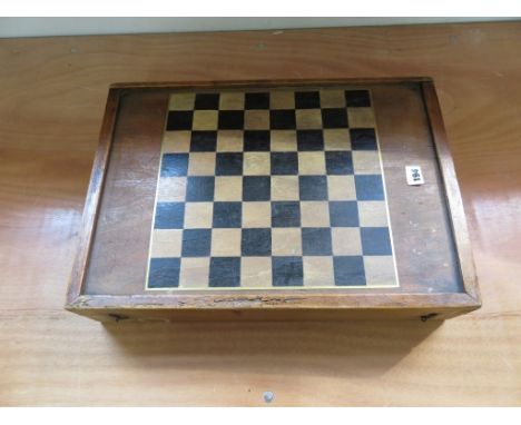 A large wooden games box with chequerboard lid, backgammon interior and containing draughts, chessmen and dominoes 