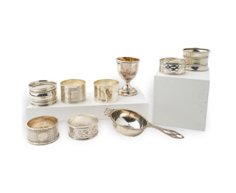 Seven 20th century silver napkin rings, various dates and makers, silver tea strainer and a silver egg cup Condition Report:A