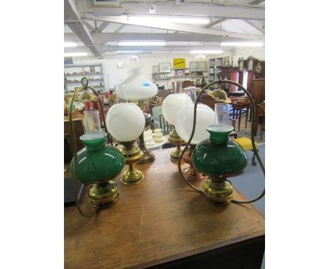A group of four brass and copper oil lamps with glass shades and smoke funnels to include a Duplex lamp, along with two brass