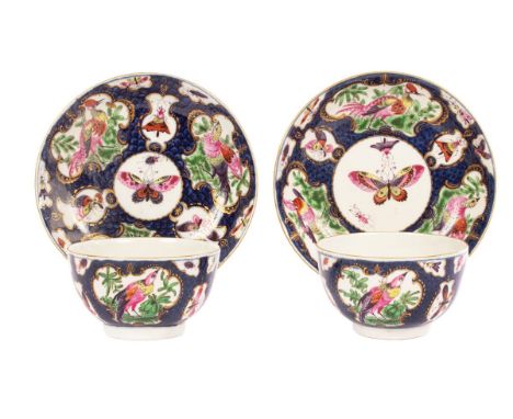 A pair of Worcester tea bowls and saucers, decorated reserves of disheveled birds, butterflies etc., on a blue scale ground, 