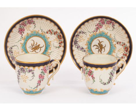 A pair of Worcester fluted coffee cups and saucers, with blue and turquoise borders painted with bouquets of flowers, within 