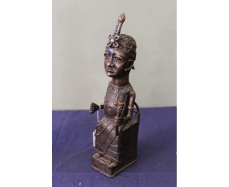 A 20th Century African 'Benin' style cast model, depicting a seated male figure wearing a head piece and necklaces and holdin