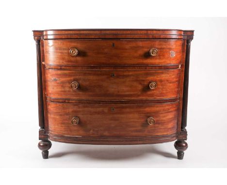 A Regency figured mahogany break bow-fronted commode chest of three long drawers. The drawers flanked by a pair of reeded tur