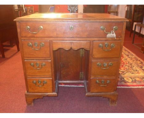 An early 19th Century George III mahogany kneehole desk, having an arrangement of drawers including a shaped frieze drawer ov