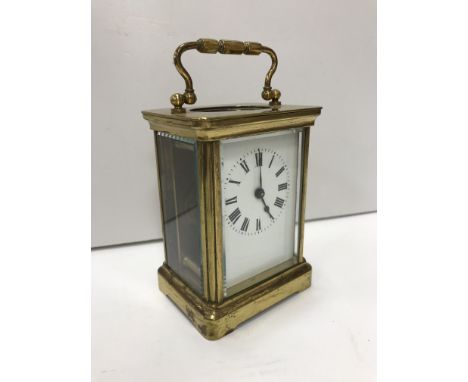 An early 20th Century brass cased carriage clock, the enamelled dial set with Roman numerals, 11cm high not including handle