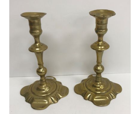 A pair of 18th Century brass candlesticks on square petal form bases 21.5 cm high together with three other brass candlestick