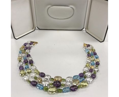 A modern three row necklace of multi-coloured semi precious polished boulder beads strung to an 18 carat gold bar snap togeth