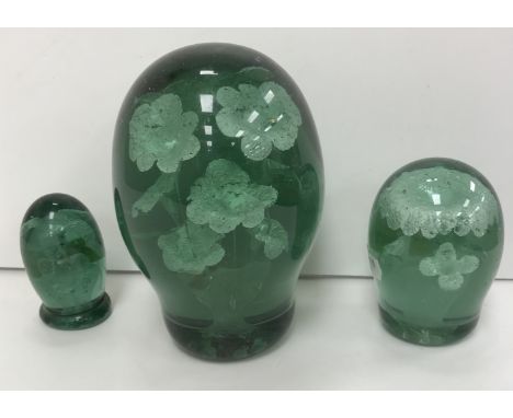 A Victorian green glass dump, the centre decorated with a vase of flowers 16 cm high together with two smaller dumps 9.5 cm h
