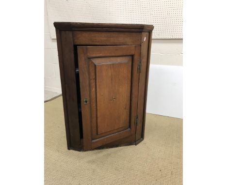 A George III oak hanging corner cupboard, the fielded panelled door with central parquetry starburst opening to reveal two sh