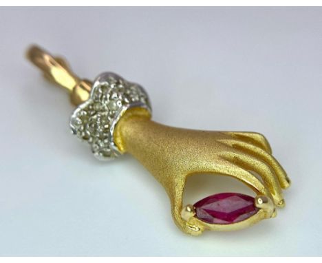 A 14K Yellow Gold, Diamond and Ruby Hand Pendant. A diamond wristed feminine hand gently caresses a pink ruby. 3cm. 2.55g tot
