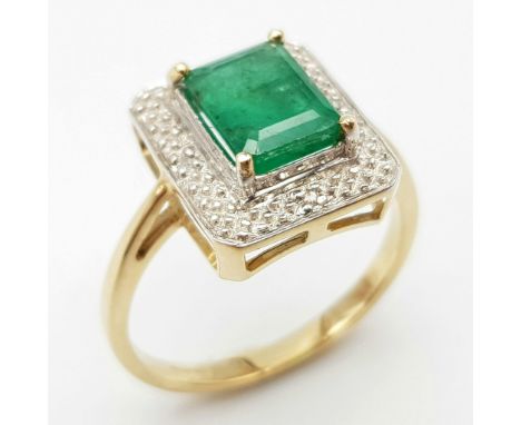 A 9K GOLD RING WITH 2.5ct NATURAL EMERALD SURROUNDED BY DIAMONDS. 3.8gms size O