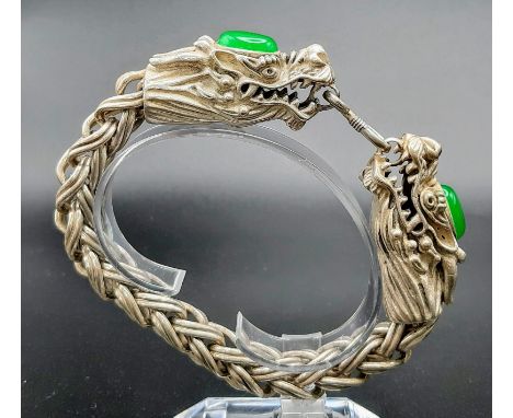 A Vintage, Chinese silver, double headed dragon bracelet with two green jade cabochons. In a presentation case.Length: 23 cm,