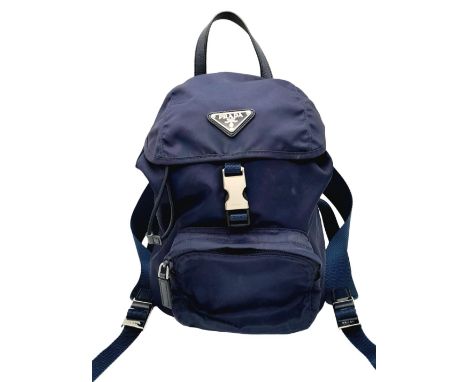 A Prada Navy Blue Mini Backpack. Textile exterior with silver-toned hardware, leather top handle, two adjustable straps, zipp