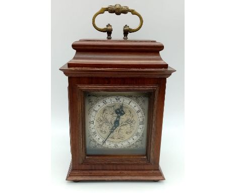 A "ROTHERHAM" CLOCKWORK MANTLE CLOCK WITH ORNATE  SCROLLED METAL DIAL . ROMAN NUMERALS AND HOUSED IN A WOODEN CASE WITH BRASS