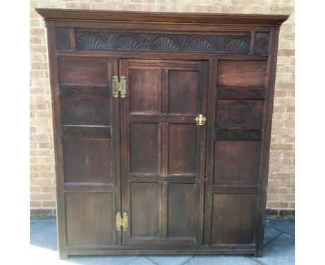 A PANELLED OAK HALL CUPBOARD with moulded frieze, lunette carved decoration to front, with pair of panels bearing intials and