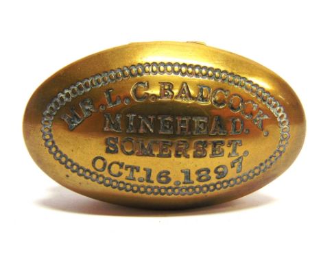 A BRASS TOBACCO OR SNUFF BOX  the lid impressed 'MR. L.C. BADCOCK / MINEHEAD / SOMERSET / OCT.16.1897', 7.5cm wide (oval).
