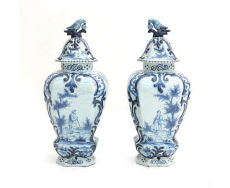  A pair of large Delft blue and white covered vases, decorated with foliate motifs, a man with a stick, a woman with a basket