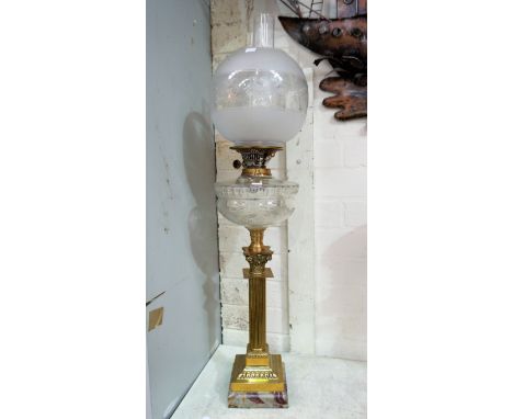 A brass Corinthian column oil lamp with glass reservoir, shade and chimney