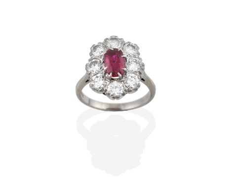 A Ruby and Diamond Cluster Ring, the oval cut ruby within a border of round brilliant cut diamonds, in white claw settings, t