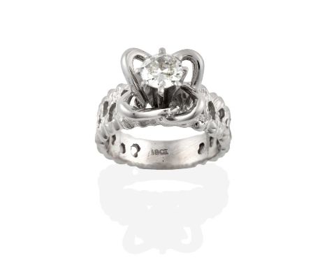 A Diamond Solitaire Ring, the round brilliant cut diamond in a white claw setting, within an openwork surround, to a textured