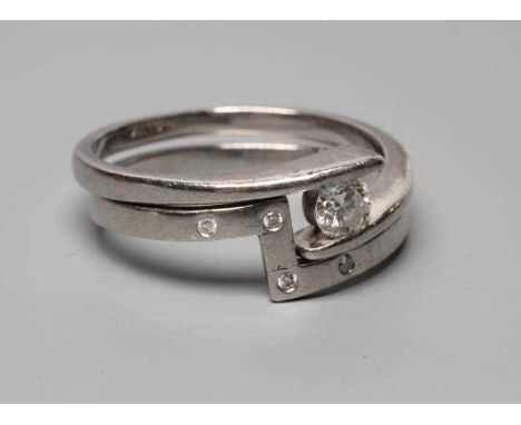 A PALLADIUM DIAMOND ENGAGEMENT AND MATCHING WEDDING RINGS, the modern crossover with a tension set round brilliant of approxi