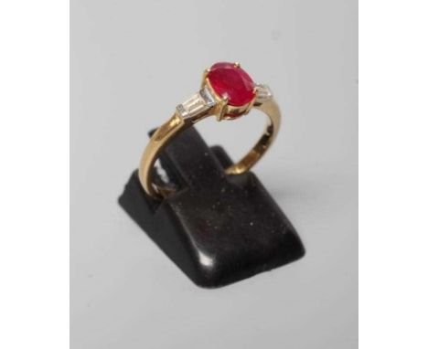 A RUBY AND DIAMOND RING, the oval facet cut ruby claw set to tapering shoulders, each channel set with two small tapering bag