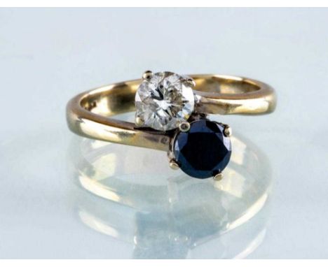 A DIAMOND TWO STONE CROSSOVER RING, the brilliant cut white and black stones each of approximately 0.5cts, claw set to a plai