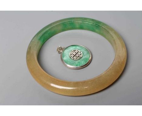 A POLISHED JADE BANGLE of D form, 37g, together with a silver mounted jade Shou pendant, stamped 925 (2) (Est. plus 24% premi