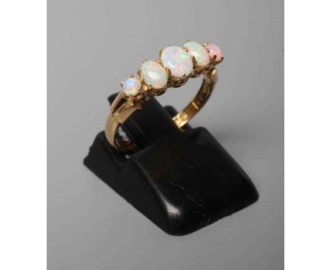 AN EDWARDIAN FIVE STONE OPAL RING, the three central graduated oval cabochon polished stones flanked by two circular stones, 