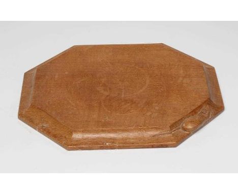 A ROBERT THOMPSON ADZED OAK BREAD BOARD of canted oblong form, the moulded edge with carved mouse trademark in high relief, 1