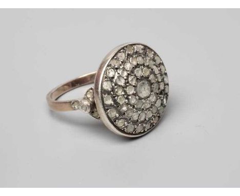 A DIAMOND TARGET RING, the circular panel point set with numerous mix cut (mostly rose cut) stones to an unmarked plain shank