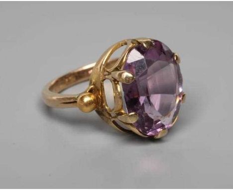AN AMETHYST DRESS RING, the oval facet cut stone claw set to bead shoulders and a plain shank stamped 18ct, size K (Est. plus