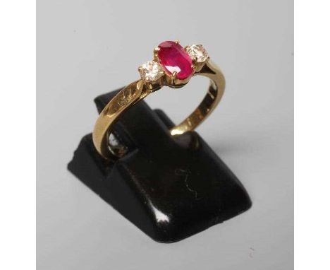 A RUBY AND DIAMOND THREE STONE RING, the central oval facet cut ruby claw set and flanked by two small brilliant cut diamonds