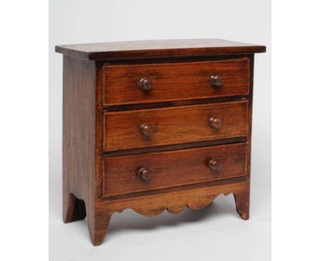 A MINIATURE MAHOGANY THREE DRAWER CHEST, 19th century, with satinwood banding and turned wood handles, shaped apron and brack