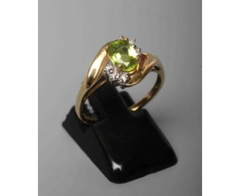 A PERIDOT AND DIAMOND DRESS RING, the oval facet cut peridot claw set within two sets of three point set small diamonds to a 